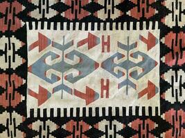 invecklad stammönstrat turkiska matta med geometrisk former och traditionell handvävd design, terar en rik blandning av färger foto