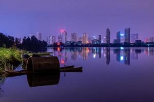 en stad som reflekteras av sjön på natten foto