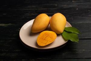 skär och färdig mango på en tallrik i en mörk miljö foto