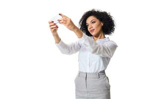 skön brunett kvinna i klassisk vit skjorta och kjol göra selfie på de telefon. foto