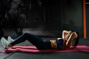 atletisk ung kvinna håller på med crunches under träna i Gym foto