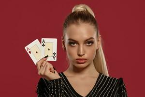 blond kvinna i svart klänning i strass. hon är som visar två ess, Framställ mot röd bakgrund. hasardspel underhållning, poker, kasino. närbild foto
