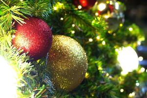 de jul träd är dekorerad med gul, röd bollar och lampor till Välkommen de festival och ny år. foto