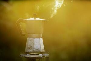 moka pott och rök, ånga från de kaffe pott på brand, i de skog på soluppgång i de morgon. mjuk fokus. grund fokus effekt. foto