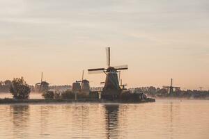 populär turist fläck zaanse schans är nära amsterdam i de väst av de nederländerna. historisk, realistisk väderkvarnar under soluppgång. hollands landmärke foto