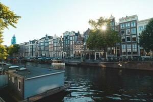 solnedgång tänds en vatten kanal och intilliggande byggnader i de huvudstad stad av amsterdam, de nederländerna. Venedig av de norr foto