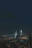 natt antenn se av de sömnlös stad av rotterdam och arkitektonisk byggnader. lysande skyskrapor och de känd erasmusbrug bro. de modern stad av de nederländerna foto