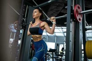 ung kvinna utför lunges på smed maskin på Gym foto