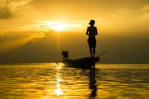 silhuetter av fiskare på de sjö med solnedgång, thailand. foto