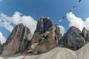 se av Tre cime di lavaredo berg med bön flaggor i de främre under en solig dag med moln och dimma i de dolomiterna, Italien. mycket känd platser för vandring och sten klättrande. foto