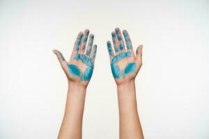 främre se av damens händer målad med blå Färg varelse Uppfostrad medan demonstrera palmer, Framställ över vit bakgrund. mänsklig händer begrepp foto