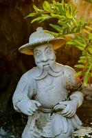 en staty av en man med en hatt och en växt foto