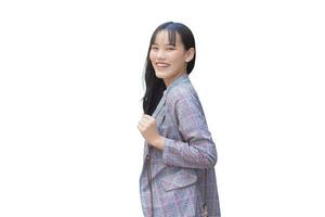 självsäker ung asiatisk kvinna vem bär en grå randig blazer och axel väska ler lyckligt och utseende på de kamera som hon pendla till arbete genom isolerat på vit bakgrund. foto