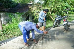 kuaro kalimantan timur, indonesien 11 november 2023. de by gemenskap var sett arbetssätt tillsammans till reparera de skadad väg foto