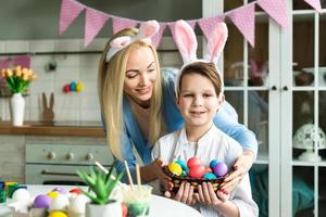 glad mamma och hennes lilla son förbereder sig för påsk, färgar ägg foto