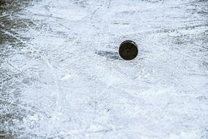 svart hockey puck lögner på is på stadion foto