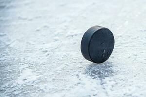 svart hockey puck lögner på is på stadion foto