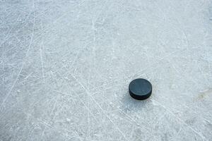 svart hockey puck lögner på is på stadion foto