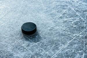 svart hockey puck lögner på is på stadion foto