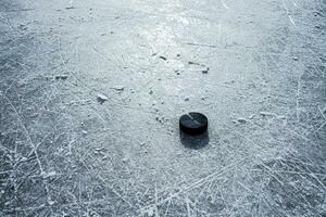 svart hockey puck lögner på is på stadion foto