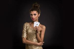 kvinna vinnande - ung kvinna i en flott guld klänning innehav två ess, en poker av ess kort kombination. foto