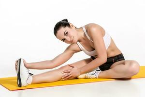 attraktiv kvinna håller på med övningar. brunett passa kropp på yoga matta foto