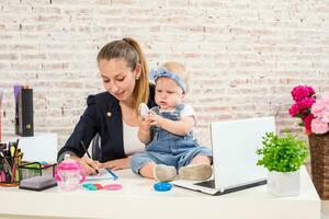 mamma och affärskvinna arbetssätt med bärbar dator dator på Hem och spelar med henne bebis flicka. foto