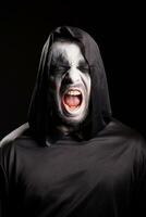 porträtt av dyster skördeman skrikande över svart bakgrund. halloween kostym. foto