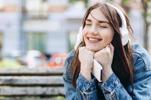 ung, leende kvinna som lyssnar på musik med hörlurar. flicka som lyssnar på låtar via trådlösa hörlurar. närbild ansikte av tonåring. foto