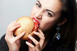flicka äter en stor hamburgare, studio Foto