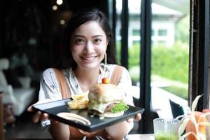 asiatiska kvinnor leende och glada och njöt av att äta hamburgare på kaffe och restaurang vid avkoppling foto