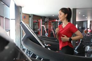 asiatiska kvinnor som kör sportskor på gymmet medan en ung kaukasisk kvinna joggar på löpbandet