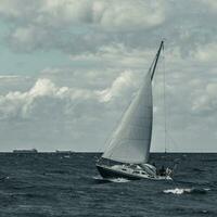 blå segelbåt i en resa på stormig hav. regata resa. tonad foto