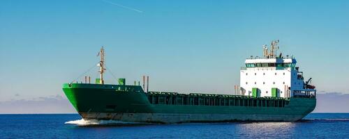 grön frakt fartyg rör på sig i fortfarande vatten av baltic hav foto