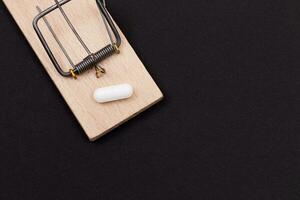farmaceutisk missbruk eller stor pharma fälla vit piller i trä- musfälla på svart bakgrund foto