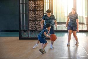 asiatisk familj som spelar basket tillsammans. lycklig familj som spenderar ledig tid tillsammans på semester foto