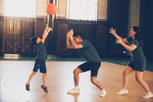 asiatisk familj som spelar basket tillsammans. lycklig familj som spenderar ledig tid tillsammans på semester foto