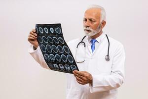 porträtt av orolig senior läkare innehav x stråle bild på grå bakgrund. foto