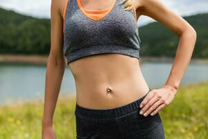 stänga upp mage av en sportig kvinna med magmuskler i de skön natur foto