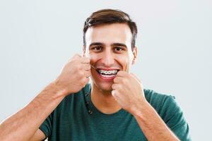 man med tandställning rengöring hans tänder med dental flock foto