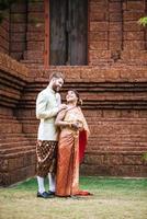asiatisk brud och kaukasisk brudgum har romantisk tid med thailändsk klänning foto