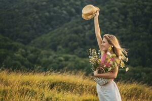 Lycklig kvinna innehav korg full av blommor och åtnjuter i de natur foto