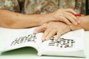 äldre kvinna spelar sudoku pussel spel för behandling demens förebyggande och alzheimers sjukdom. foto