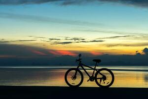 silhuett av en cykel på en sjö på skymning. foto