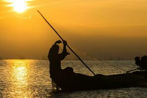 silhuett fiskare och solnedgång himmel på de sjö. foto