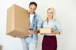 människor, leverans, frakt och post service begrepp - Lycklig par öppning kartong låda eller paket på Hem foto