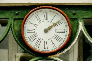en klocka på de sida av en grön byggnad foto