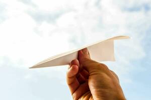 en person innehav en papper flygplan i de luft foto