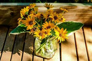 en vas av gul solrosor på en trä- tabell foto