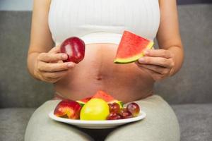 gravid kvinna äter frukt vattenmelon äppeldruva foto